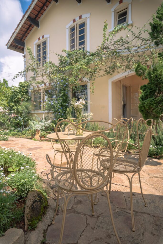 Vintage metal chairs on a charming garden patio outside a quaint house, perfect for outdoor relaxation.
